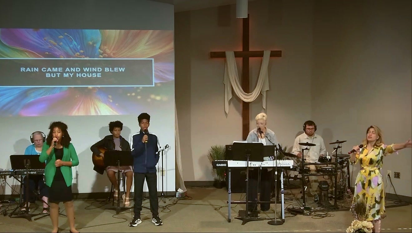 Worship team leading Sunday worship beneath the cross at Waseca Christian Assembly